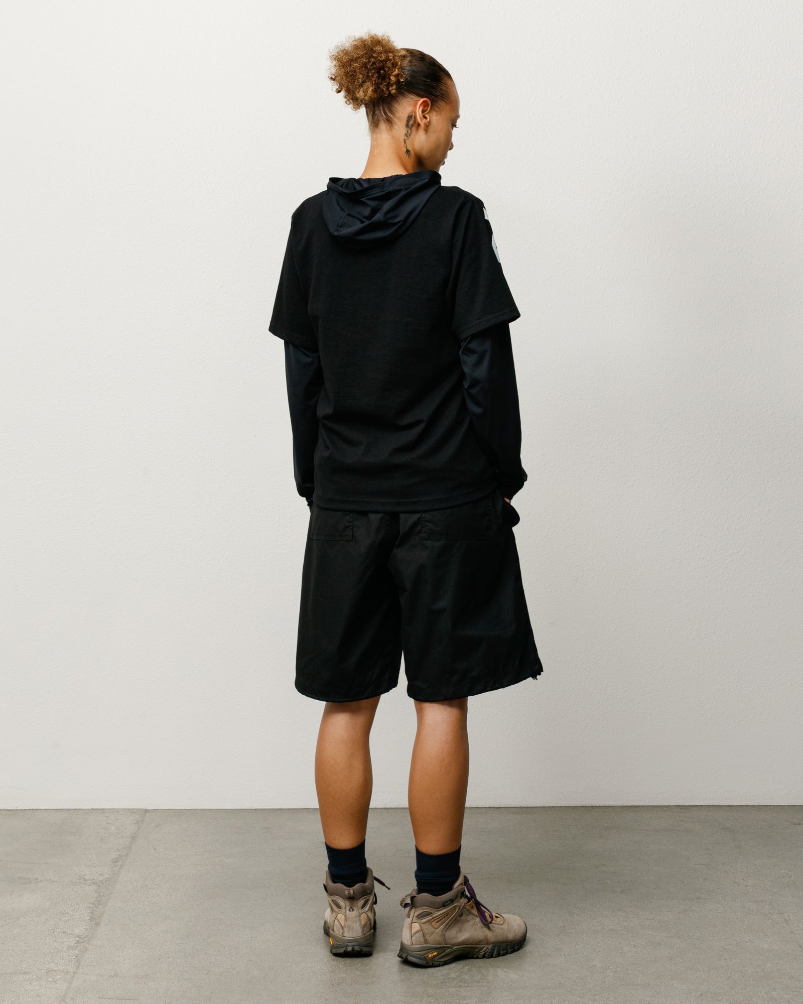 Black unisex baggy shorts with rear pockets, shown on model from the back