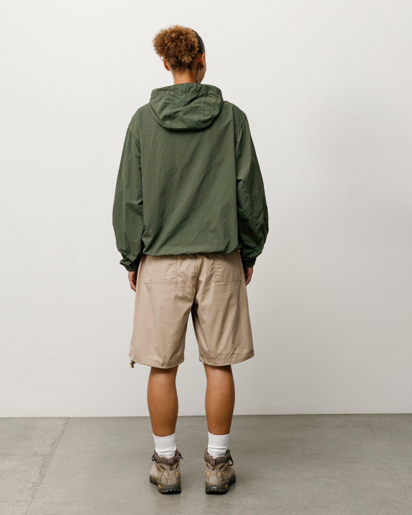 Khaki surplus shorts with baggy fit, rear patch pockets and adjustable hem drawcords, shown on model.