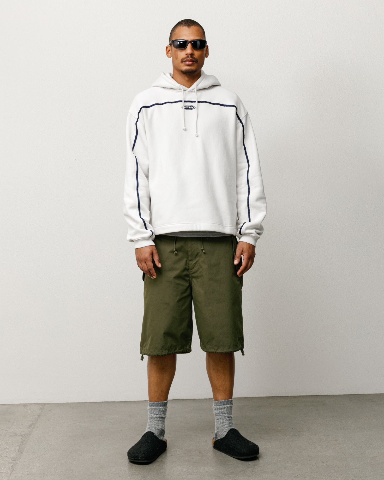 Olive baggy unisex shorts with drawcord waist and hem, styled on model front-on