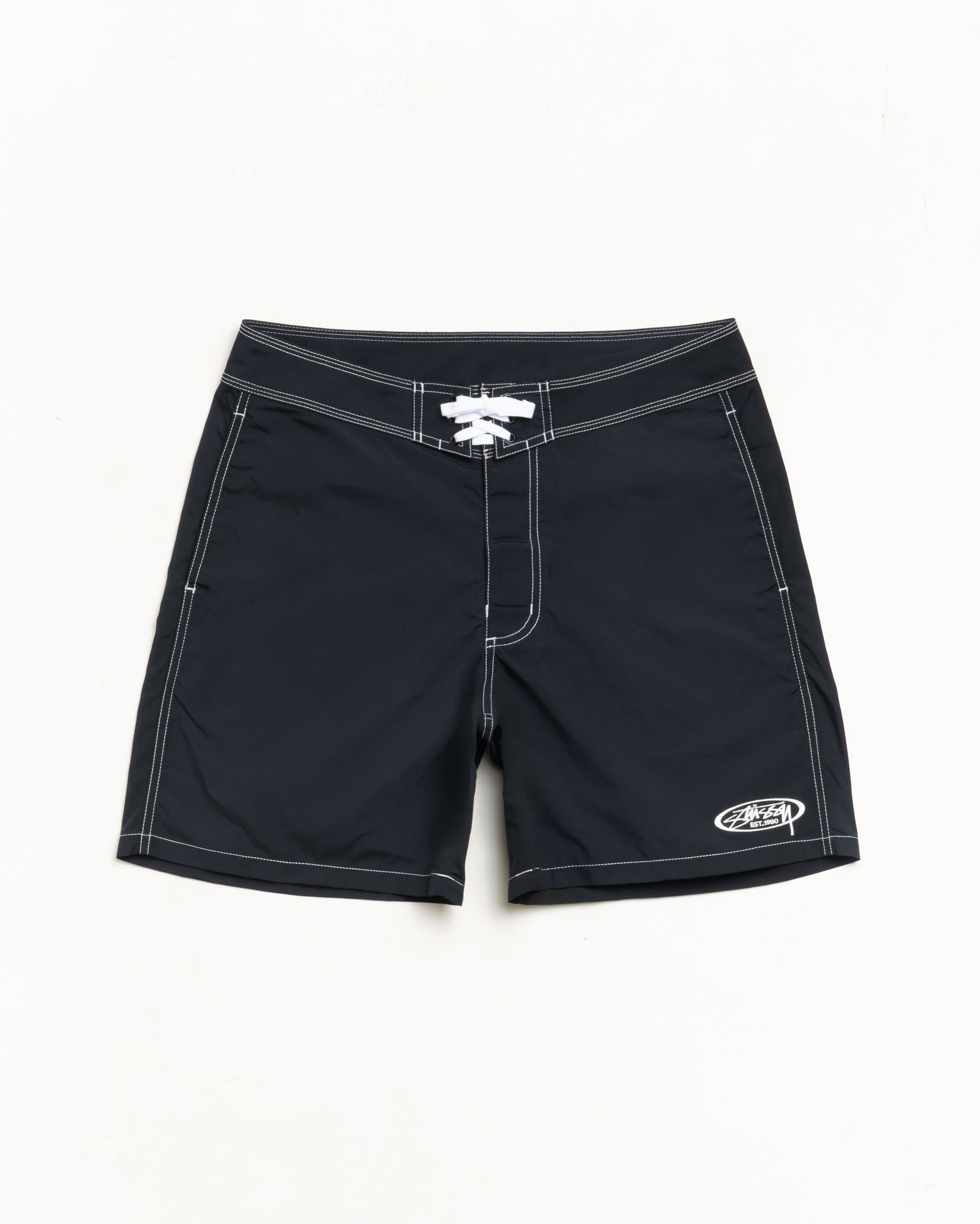 Black board shorts with contrast white stitching, lace-up waist and small logo at hem