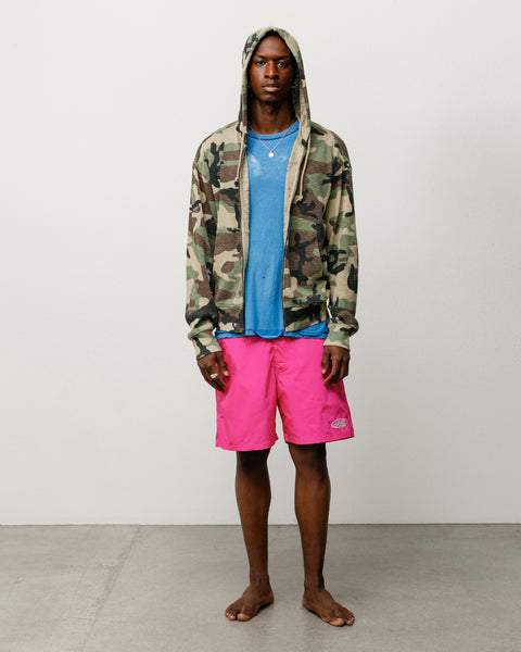 Pink unisex board shorts on model with drawcord waist and logo at hem