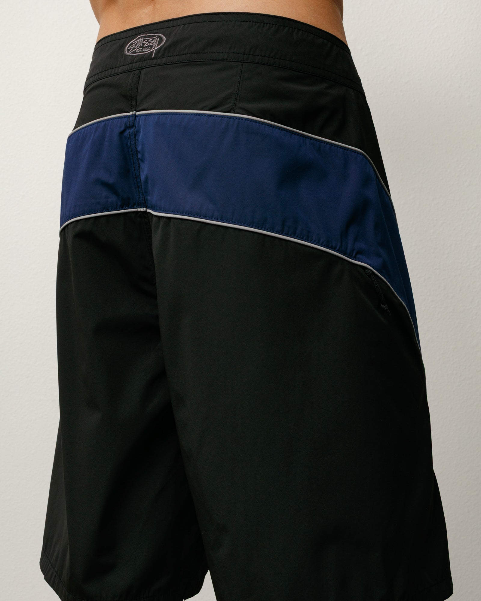 Boardshorts Cove Board Short noirs, panneau contrastant marine et broderie Stüssy à la taille dos.