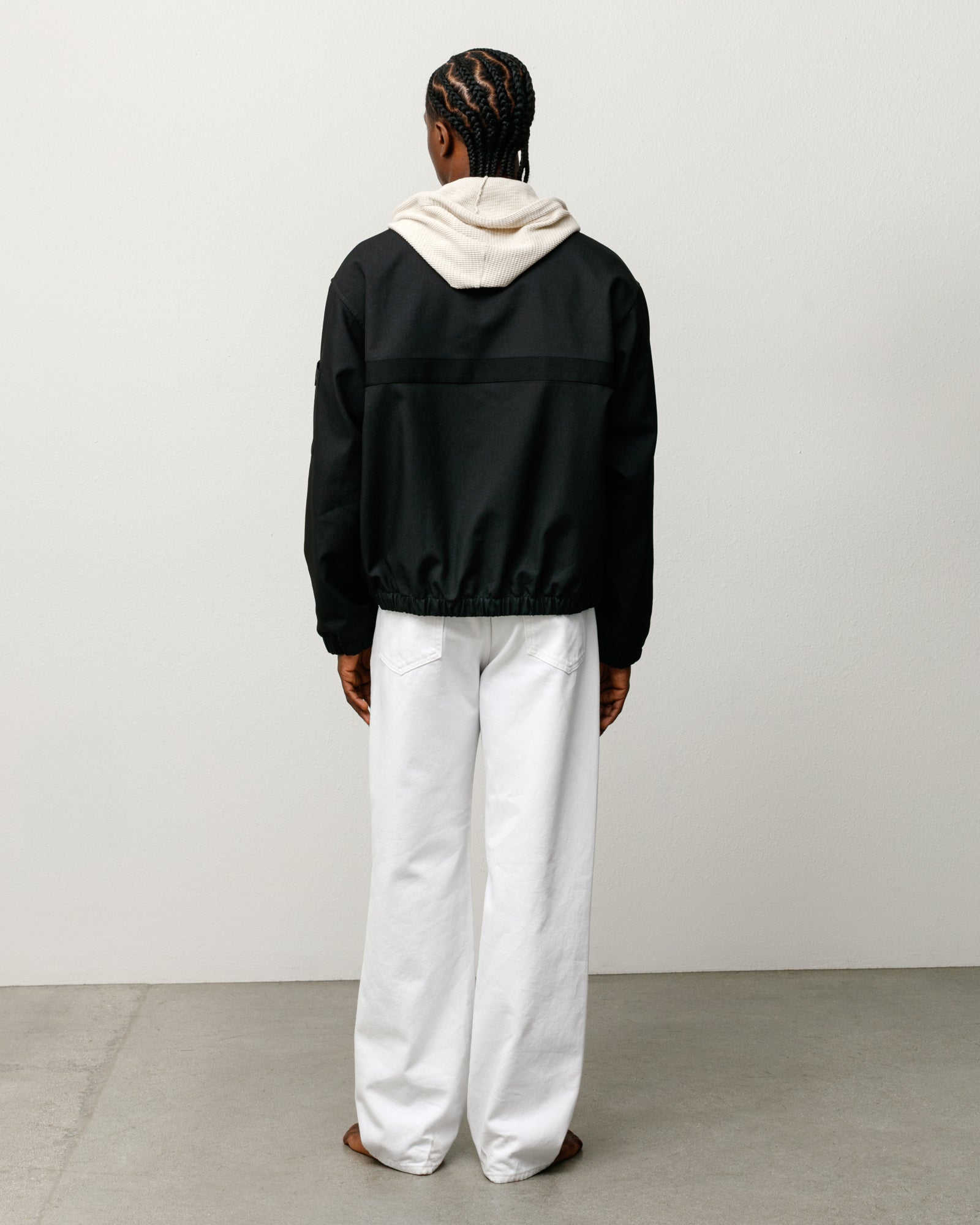 Black mechanic jacket, back view with boxy fit and elastic hem, layered over a hoodie