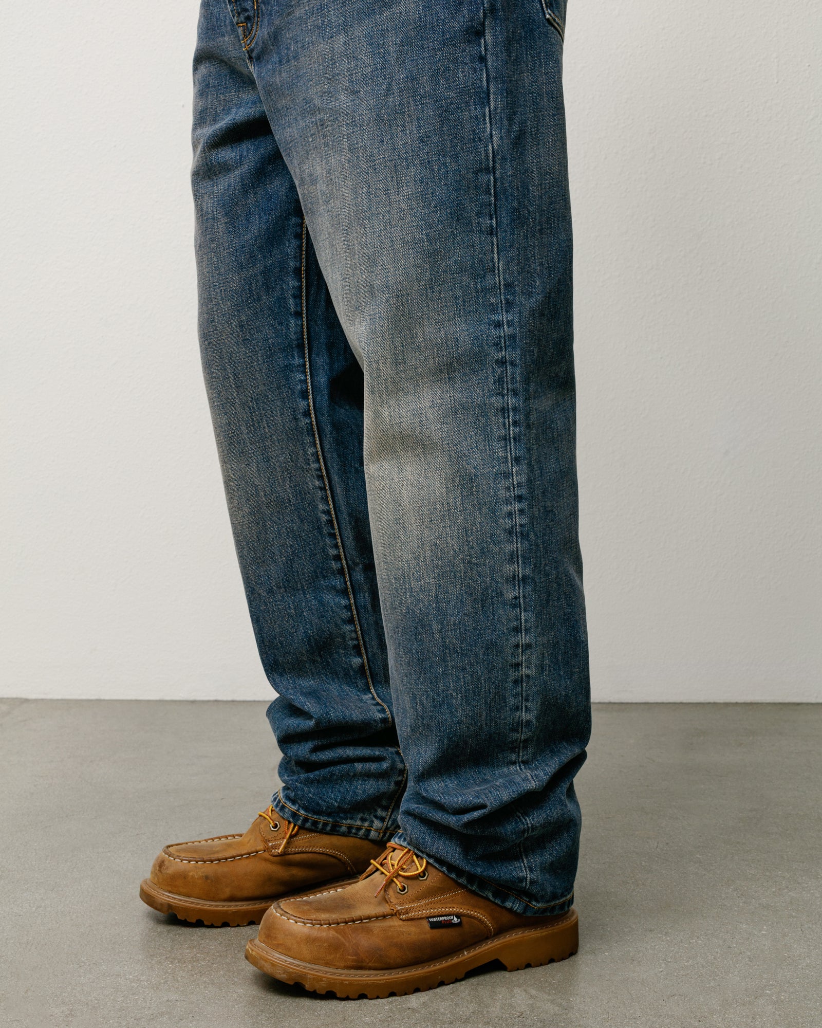 Blue slub denim straight-fit jeans on model, styled with brown moc-toe boots.