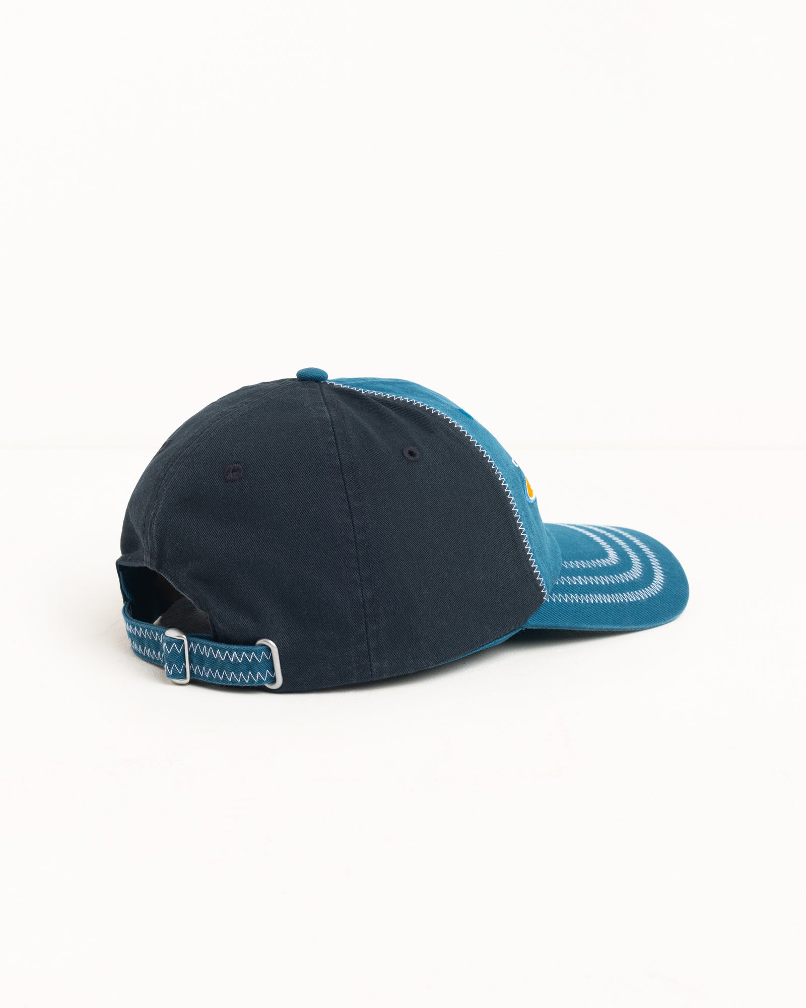 Two-tone blue low-profile six-panel cap with contrast zig-zag stitching and strapback