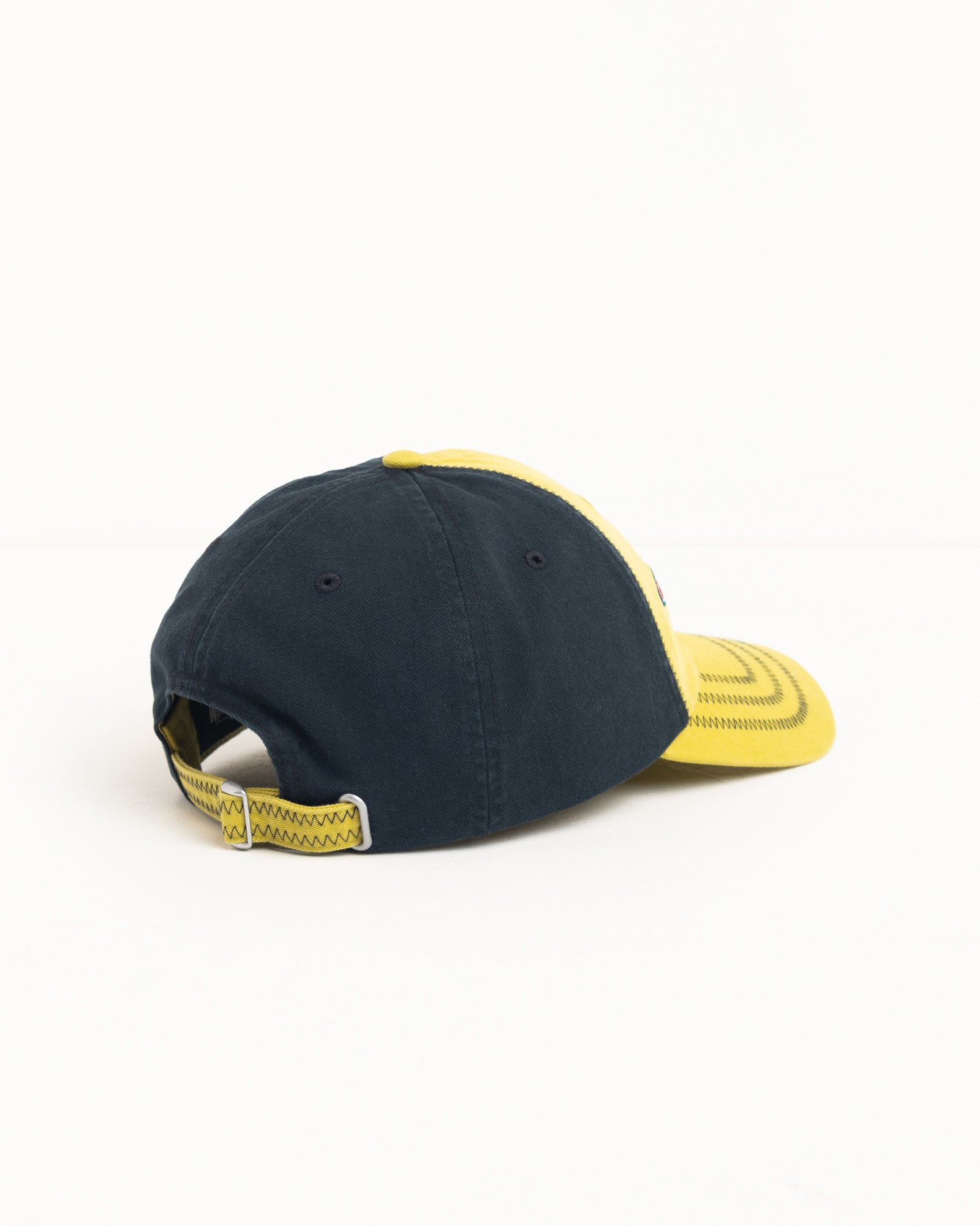Low-profile two-tone lime and navy cap, back view with metal strapback and zig-zag stitching