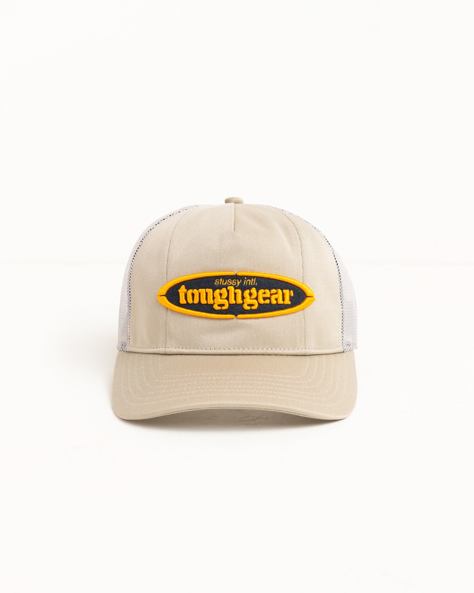 Khaki trucker cap with mesh back, precurved brim, and raised yellow oval logo patch.