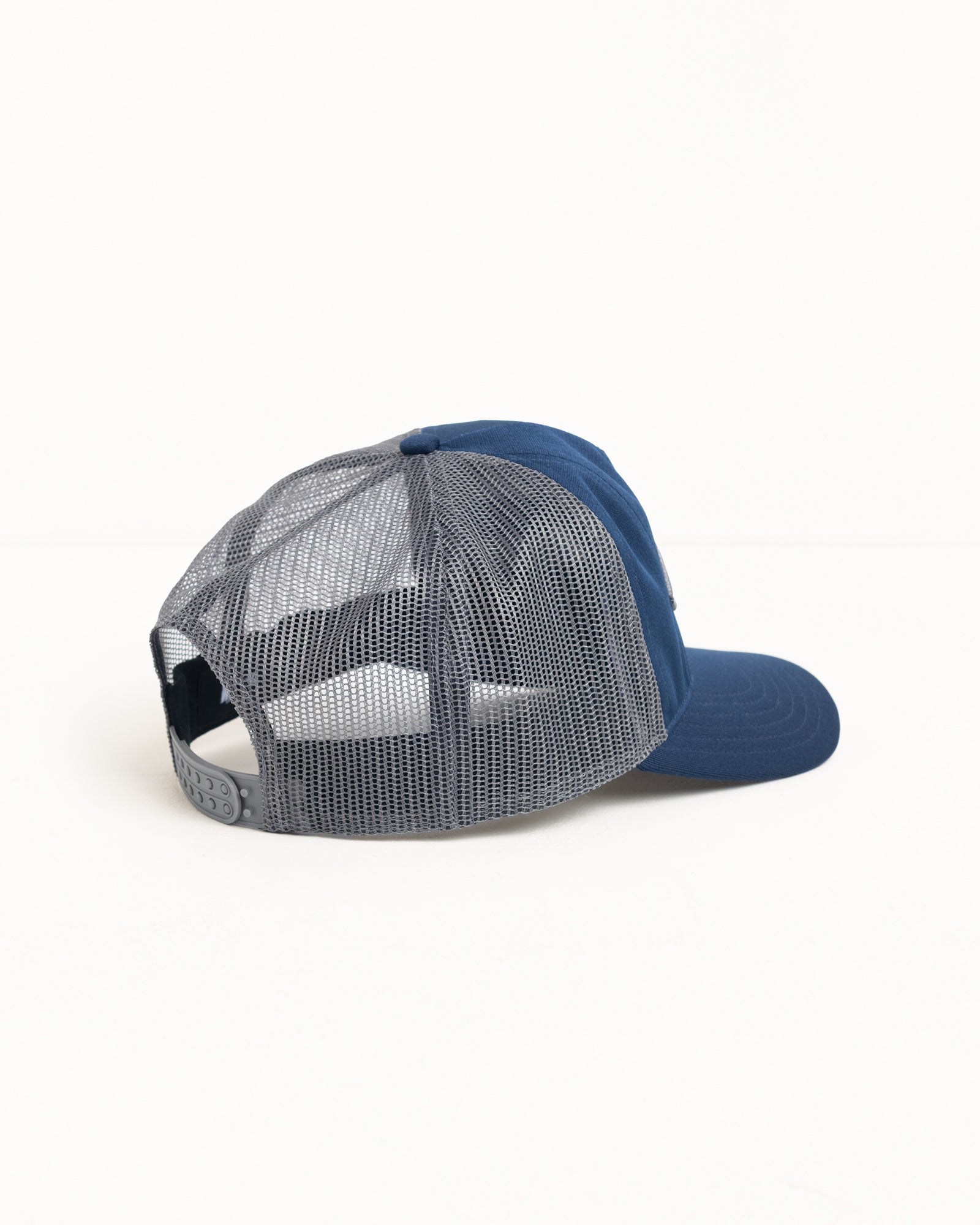 Navy trucker cap with grey mesh back and adjustable snapback closure.