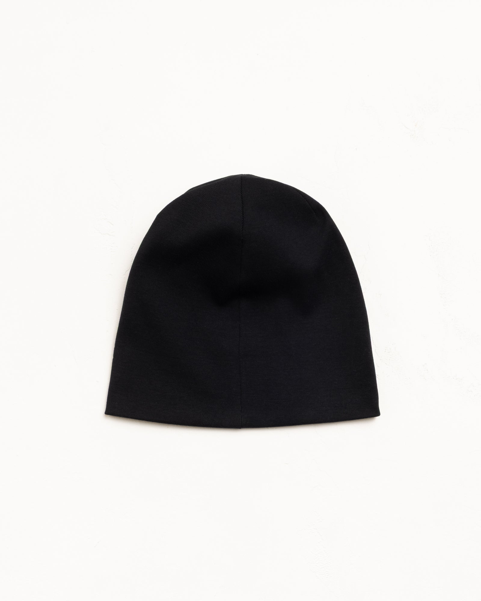 Black jersey skullcap beanie laid flat on a white background