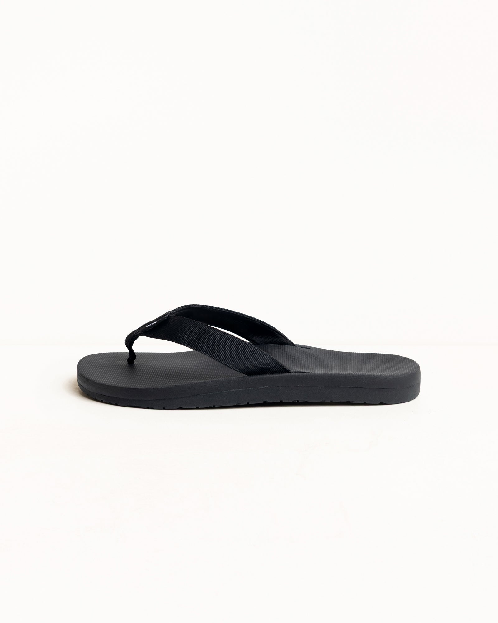 Black rubber flip-flop with wide straps and contoured footbed, side view