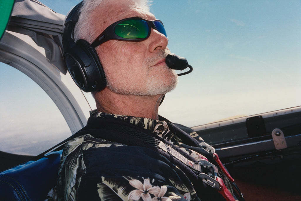 Pilot flying a plane and wearing the Adrian Sunglasses in Frost Grey/Green Mirror Lens.